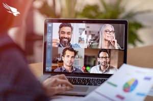 person at keyboard with zoom meeting on monitor